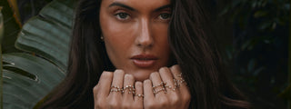 Close up of Elsa Hosk lying down with her hands on her shoulder, wearing Logan Hollowell Constellation Rings